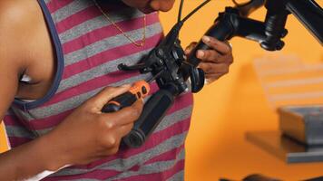 Woman uses screwdriver to make sure brake levers are secure on handlebars in studio background atelier shop. Close up shot of expert mechanic unscrewing bike parts in order to mend them photo