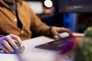 Man doing software quality assurance using keyboard and mouse, reading source code on computer. System administrator inspecting coding on desktop PC, looking to fix potential issues, close up shot photo