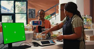 Shopper purchasing goods next to greenscreen on monitor, isolated mockup template on pc at cash register in supermarket. Vendor working with display running copyspace layout. Tripod shot. photo