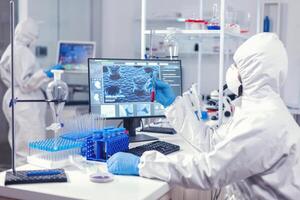 Scientist checking tube with blood analysis dressed in ppe during coronavirus epidemic. Doctor working with various bacteria and tissue, pharmaceutical research for antibiotics against covid19. photo