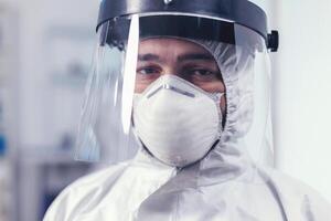 Close up of wearied chemist in laboratory wearing ppe equipment during mondial outbreak with covid19. Overworked researcher dressed in protective suit against invection with coronavirus during global epidemic. photo