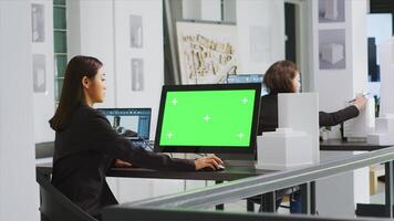 arquitecto utilizando computadora con pantalla verde a puesto de trabajo en agencia oficina, mirando a blanco Bosquejo modelo en monitor. ingeniero empleado a un real inmuebles pequeño negocio. trípode disparo. foto