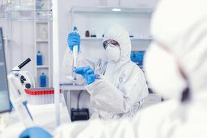 Medical scientist developing coronavirus vaccine in science lab holding micropipette. Team of microbiologists in research laboratory conducting experiment during global pandemic with covid19. photo