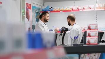 Team of employees providing full stock of medical goods in a pharmacy, counting all pill boxes and nutritional vitamins on shelves. Drugstore staff members working together to do inventory list. photo