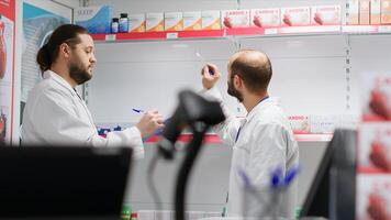 equipo de farmacéuticos asegurando productos valores en un farmacia, contando todas medicamentos y dietético suplementos en estantes. farmacia personal miembros trabajando juntos a hacer inventario. foto