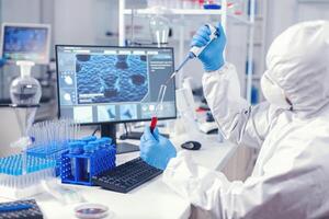 médico ingeniero utilizando dispensador a tomar muestra de sangre desde prueba tubo en laboratorio. médico trabajando con varios bacterias y tejido, farmacéutico investigación para antibióticos en contra COVID-19. foto