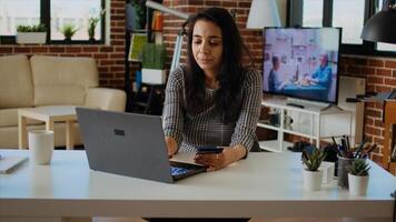 Happy woman stoked on doing online shopping, carefully typing credit card information on laptop. Indian person adding payment method on website while in cozy stylish warm home, camera A panning shot photo