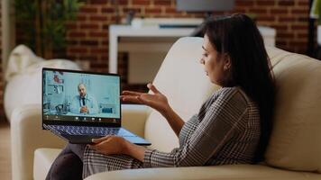 Patient sitting on couch, receiving treatment plan from medic during online videocall meeting after medical checkup. Indian person receiving prescription from GP in telemedicine call, camera B photo