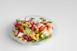 Salted vegan salad with fresh green lettuce, cucumbers, tomato, bell pepper and red onion. Ketogenic, keto or paleo diet lunch bowl. Top view. Copy space, banner, white background photo