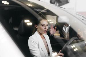 Surprised woman driver inside car choosing automobile in salon. Client smile, enjoy sitting in luxury auto buying new transport. Buy vehicle rent service rental test drive choose photo