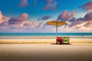 playa sillas en el arena playa con dramático cielo a puesta de sol foto