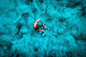 Old fisherman hands sewing blue fishing nets sitting on the ground and surrounded big net photo