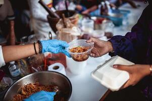 The hand of the wanderer extends to receive food from donations. With volunteers scooping food. the idea of helping with hunger photo