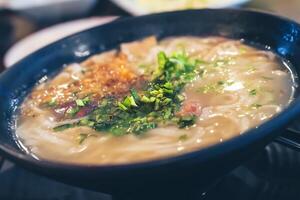 Close up. Vietnamese noodles in a black bowl topped with chopped spring onions. photo