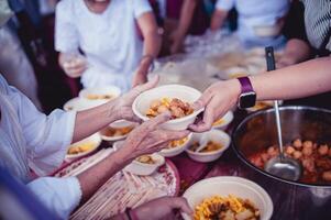 el mano de el vagabundo extiende a recibir comida desde donaciones con voluntarios recogiendo alimento. el idea de Ayudar con hambre foto