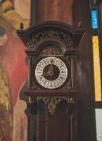 Antique old wooden wall clock displaying Roman and Arabic numerals. photo