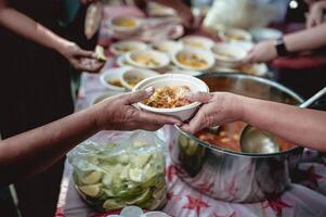 The hand of the wanderer extends to receive food from donations. With volunteers scooping food. the idea of helping with hunger photo