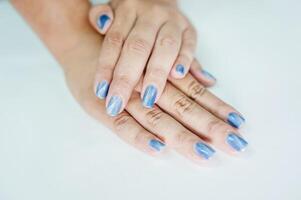 manos de un asiático mujer decorando uñas con perla azul pintar. foto