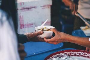 Volunteers are giving free food to help the hungry poor concept of food sharing photo