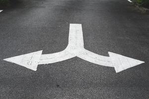 White arrow symbols pointing left and right give directions on the road. photo