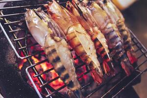 Large prawns are placed on an iron griddle and grilled over a hot coal stove. photo