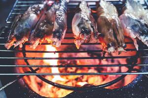 Large prawns are placed on an iron griddle and grilled over a hot coal stove. photo