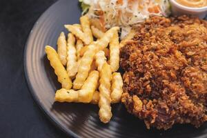 Pork batter with potato sticks and mayonnaise on a black plate photo