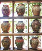Ancient-style pottery jars are lined up on wooden shelves. photo
