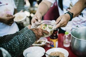 dando gratis comida a el pobre por humano personas foto