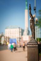 Bronze sculpture of figure holding raised object in old town Riga, Latvia. photo