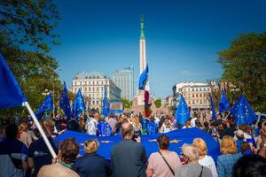 Vibrant celebration in old town of Riga, Latvia, with flags and iconic Freedom Monument photo