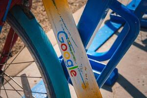 Colorful Google Logo Bicycle Frame Leaning on Blue Structure Outdoors photo