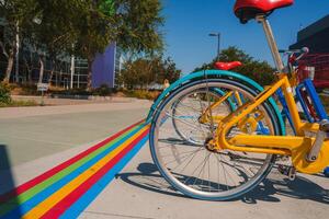 Vibrant colored bicycle parked on colorful path with modern building in background photo