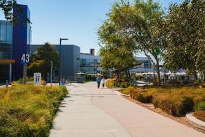 Modern Campus Scene with Building 43, Pedestrian Bridge, and Activity in Sunny Setting photo