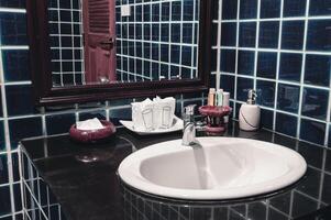 Faucet in a white sink in a bathroom with blue wall tiles photo