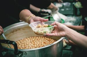 voluntarios son Ayudar a dar gratis comida a el hambriento sin hogar. comida Servicio y comida donación concepto foto