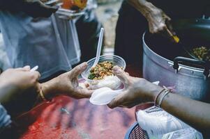 voluntarios son Ayudar a dar gratis comida a el hambriento sin hogar. comida Servicio y comida donación concepto foto