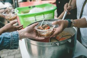 voluntarios son Ayudar a dar gratis comida a el hambriento sin hogar. comida Servicio y comida donación concepto foto