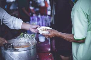 Volunteers are giving free food to help the hungry poor concept of food sharing photo