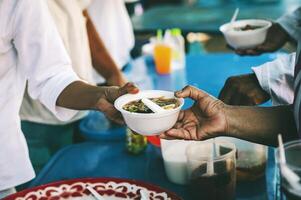 voluntarios dar comida a el pobre, compartir gratis comida a ayuda mendigos comida donación concepto foto