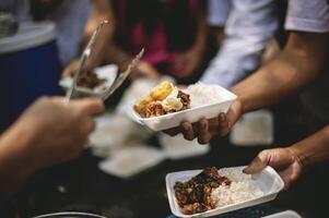 Homeless people reach out to receive free food that volunteers bring. to help alleviate hunger photo