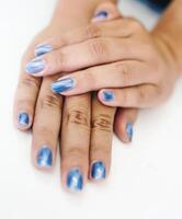 manos de un asiático mujer decorando uñas con perla azul pintar. foto