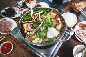 caliente maceta con claro sopa, cerdo, pez, verduras, blanqueado en caliente caldo y sumergido en un variedad de salsas foto