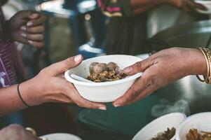 The concept of sharing food to hungry and starving people Volunteers are handing out food to the poor. photo