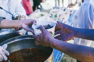 manos de hambriento personas preguntando para gratis comida desde voluntarios humanitario ayuda concepto foto