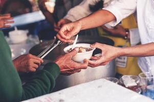 Volunteers are giving free food to help the hungry poor concept of food sharing photo