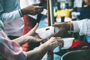 Volunteers are giving free food to help the hungry poor concept of food sharing photo