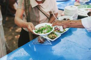 Volunteers are giving free food to help the hungry poor concept of food sharing photo