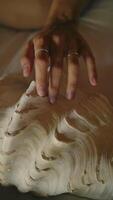 A woman's hand slowly strokes a large seashell, vertical video