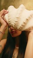 Mädchen mit Tätowierungen Abdeckungen ihr Gesicht mit ein groß Ozean Hülse, Vertikale video